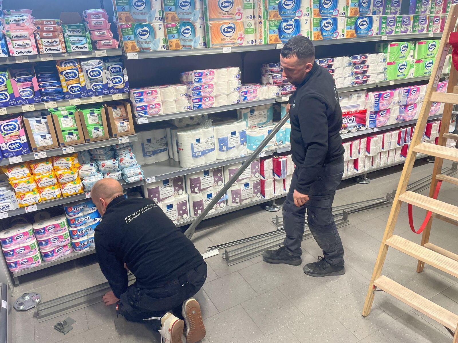 Monteure arbeiten an einer bestückten Regalanlage während der Öffnungszeiten
